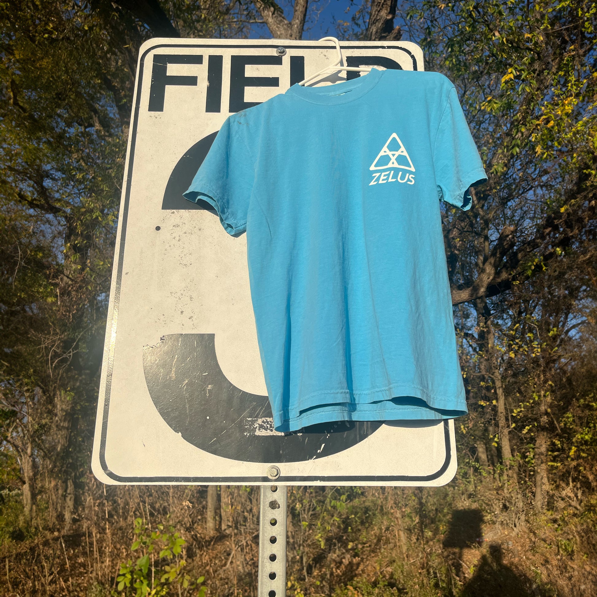 Bright Blue Short Sleeve Zelus T-Shirt Front on Soccer Field Sign